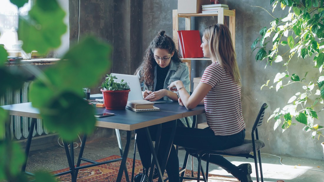 Dos personas conversando y trabajando juntas